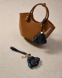 Close-up of handmade Poodle leather bag charm — hand-layered topknot curls in French Alran goatskin, hand-stitched edges. STICKYZOO Amsterdam design.