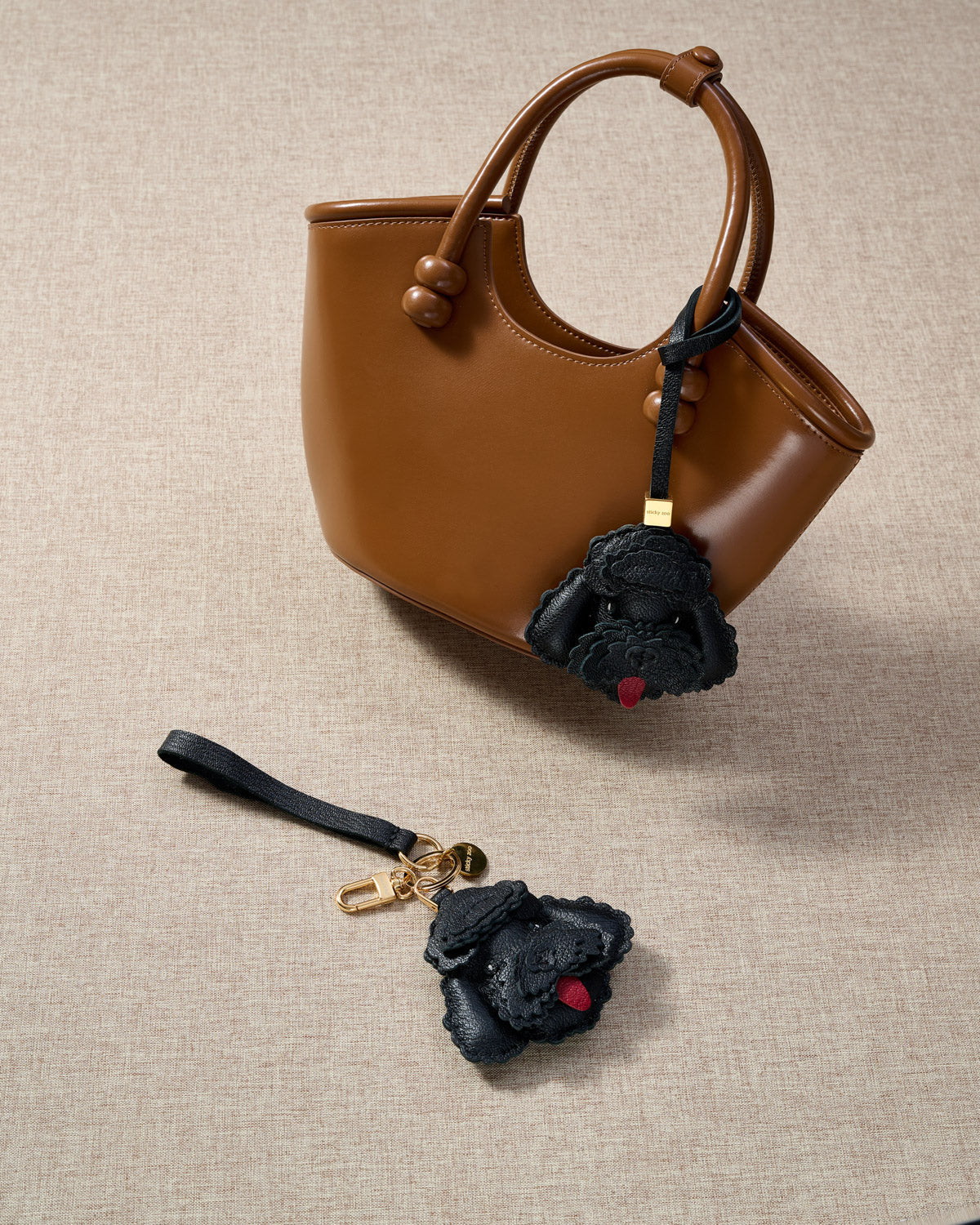 Close-up of handmade Poodle leather bag charm — hand-layered topknot curls in French Alran goatskin, hand-stitched edges. STICKYZOO Amsterdam design.