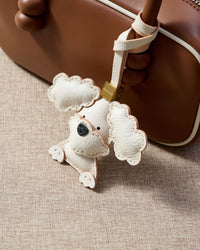 Close-up of handmade Poodle leather bag charm — hand-layered topknot curls in French Alran goatskin, hand-stitched edges. STICKYZOO Amsterdam design.