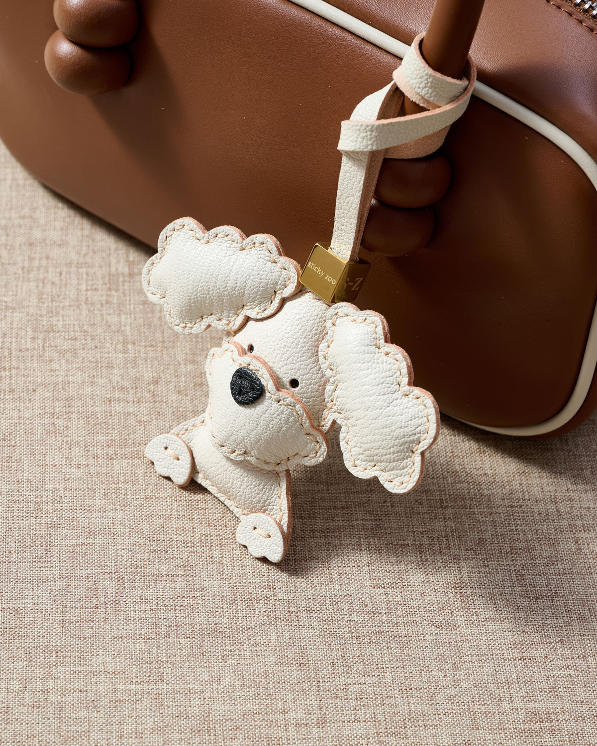 Close-up of handmade Poodle leather bag charm — hand-layered topknot curls in French Alran goatskin, hand-stitched edges. STICKYZOO Amsterdam design.
