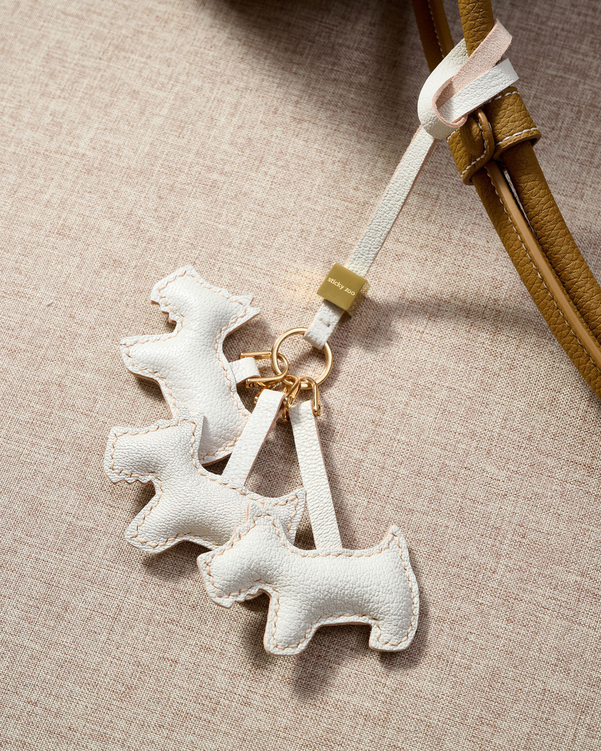 The triple schnauzer charm is made from genuine French Alran goatskin and French suede — real full-grain leather. Never vegan. Never synthetic. The difference shows.