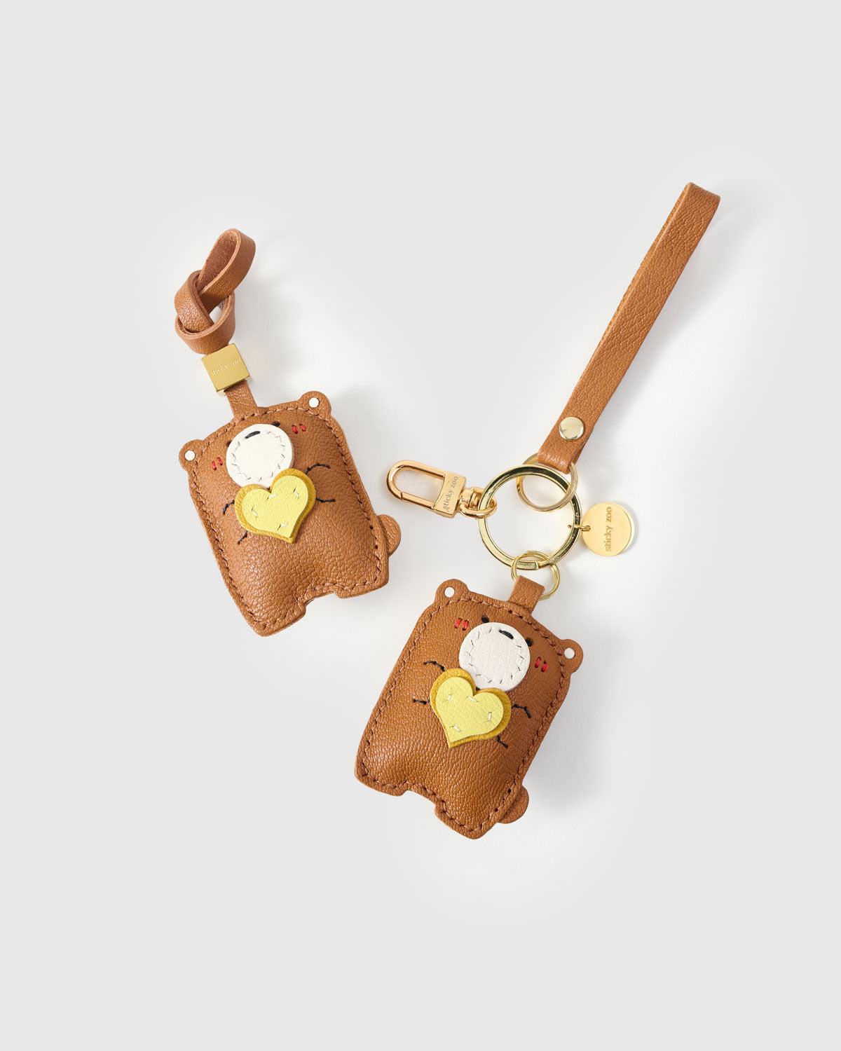 Both editions of the teddy bear charm — leather strap loop for bags, or 18K gold-plated keychain clip.