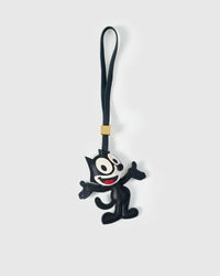 The Cat charm handmade from French Alran genuine goatskin — black body in mid-dance pose, white face with big eyes, red smile, black leather strap. Three days by hand. Arrives in luxury gift packaging. Designed in Amsterdam.