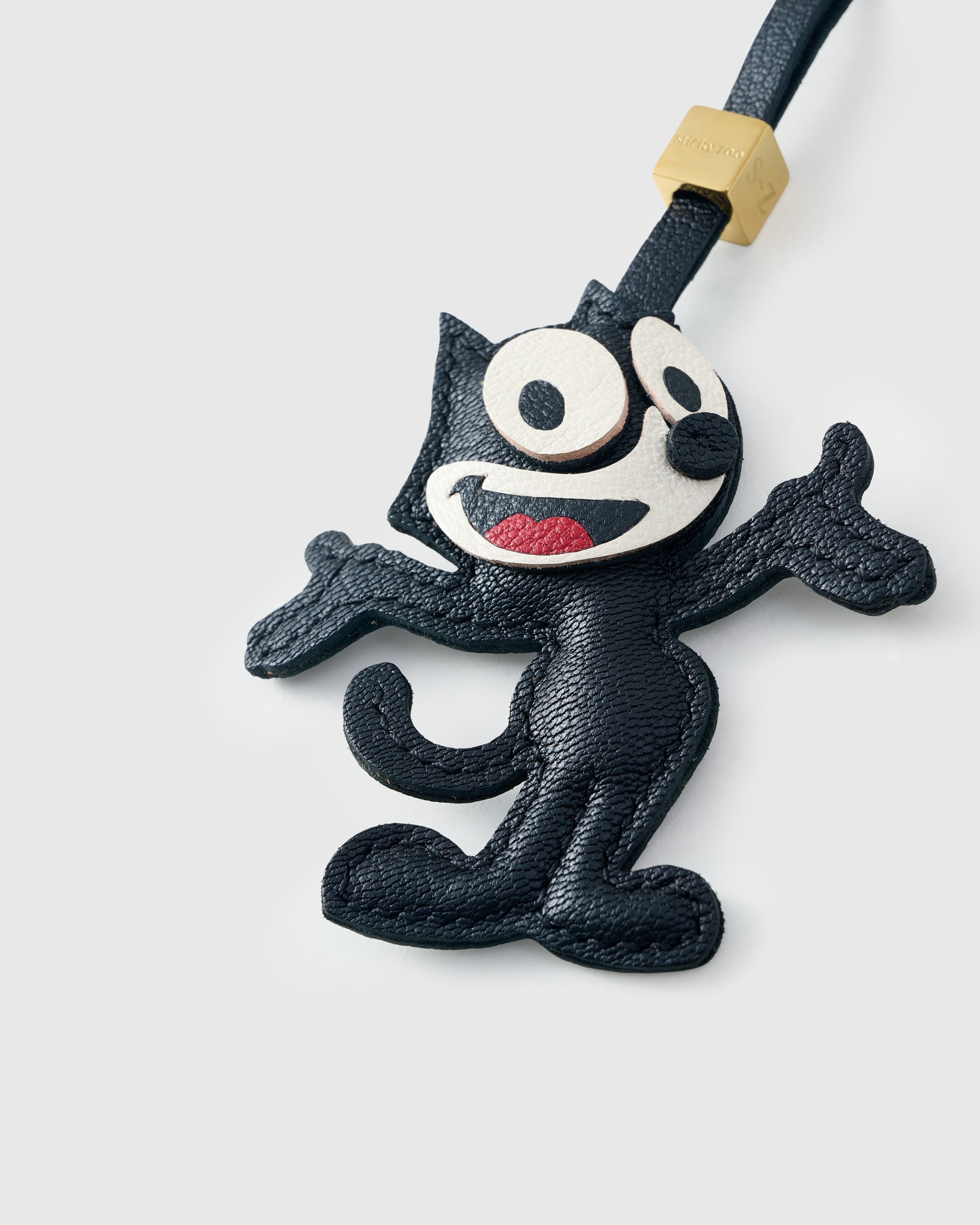 Tight close-up of the cartoon cat charm face — every detail in real French Alran leather, layered and stitched by hand.