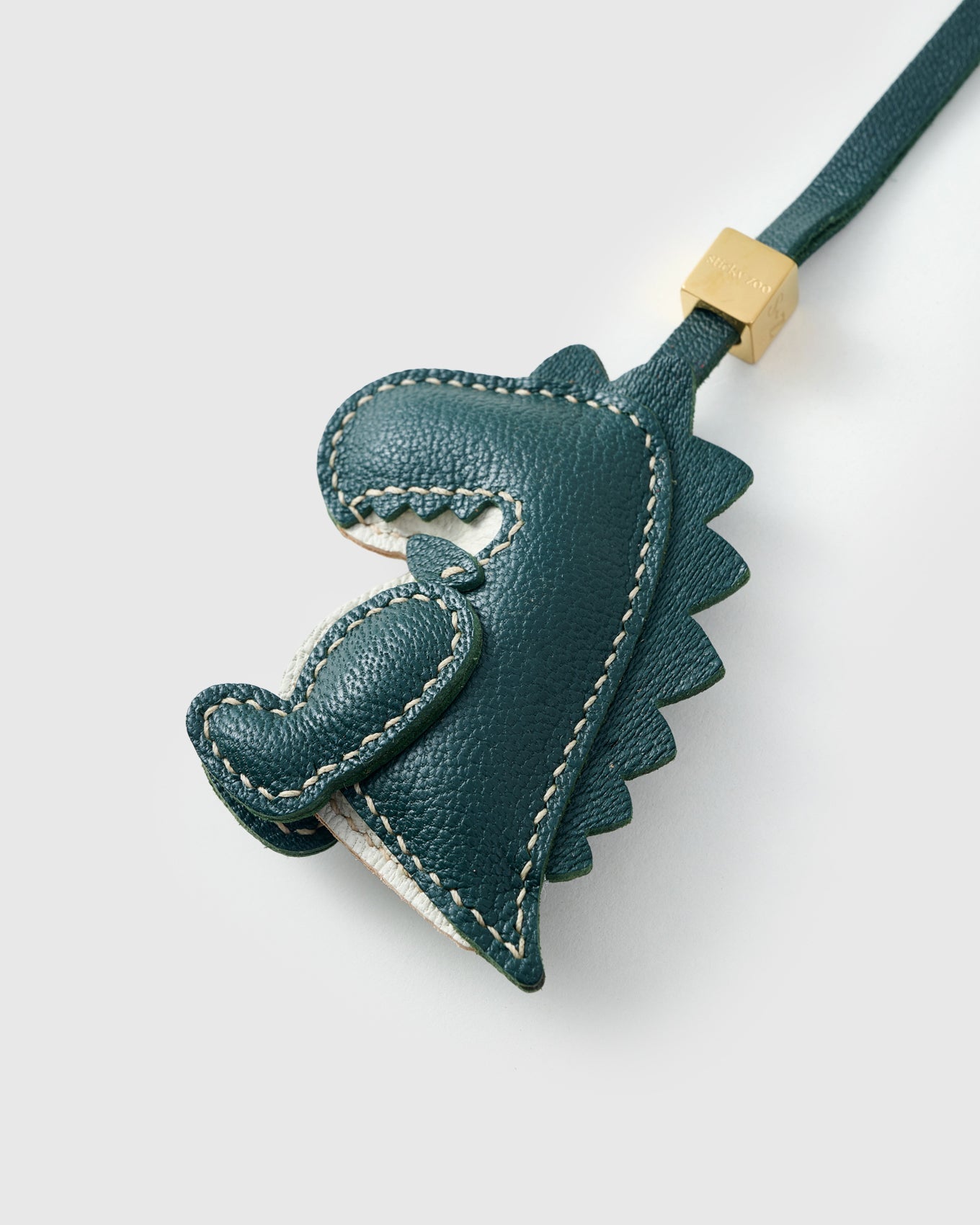 Green dinosaur charm on a bag, side angle — rated 4.9★ by thousands of buyers. Real French Alran leather, 3 days by hand.