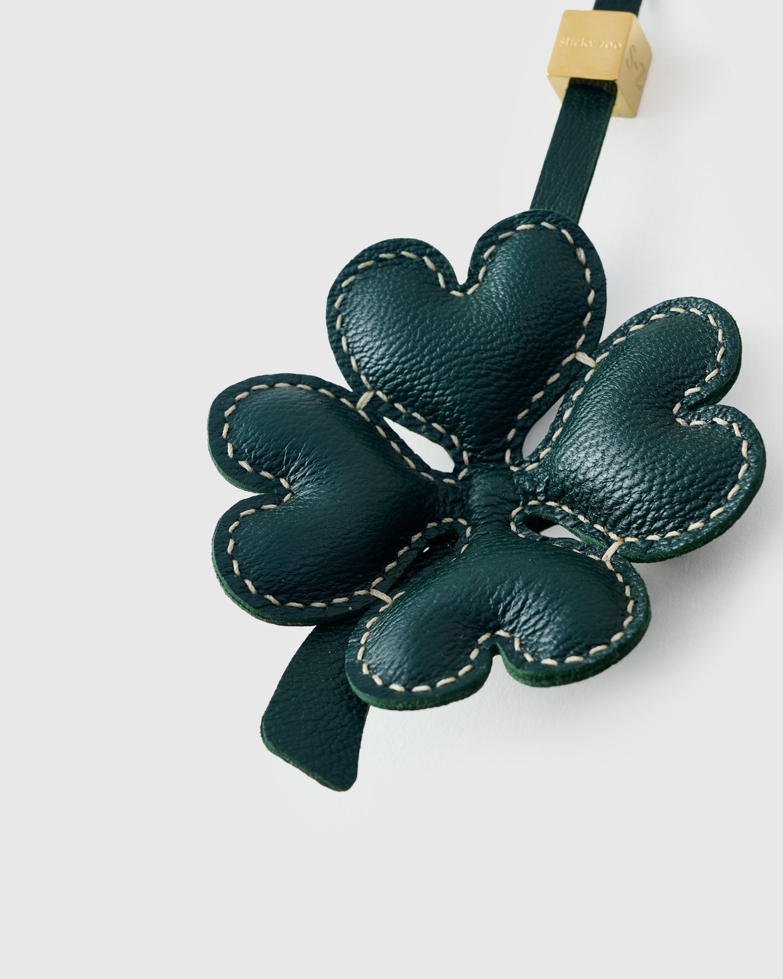 Close-up of STICKYZOO Lucky Clover Charm — full-grain French Alran goatskin from Tarn, France. Padded heart-shaped petals with contrast stitching. 3-day handmade piece.