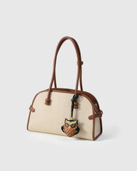 Owl charm on a cream canvas bag, side angle — loved by thousands of bird lovers. Real French leather, 3 days by hand.