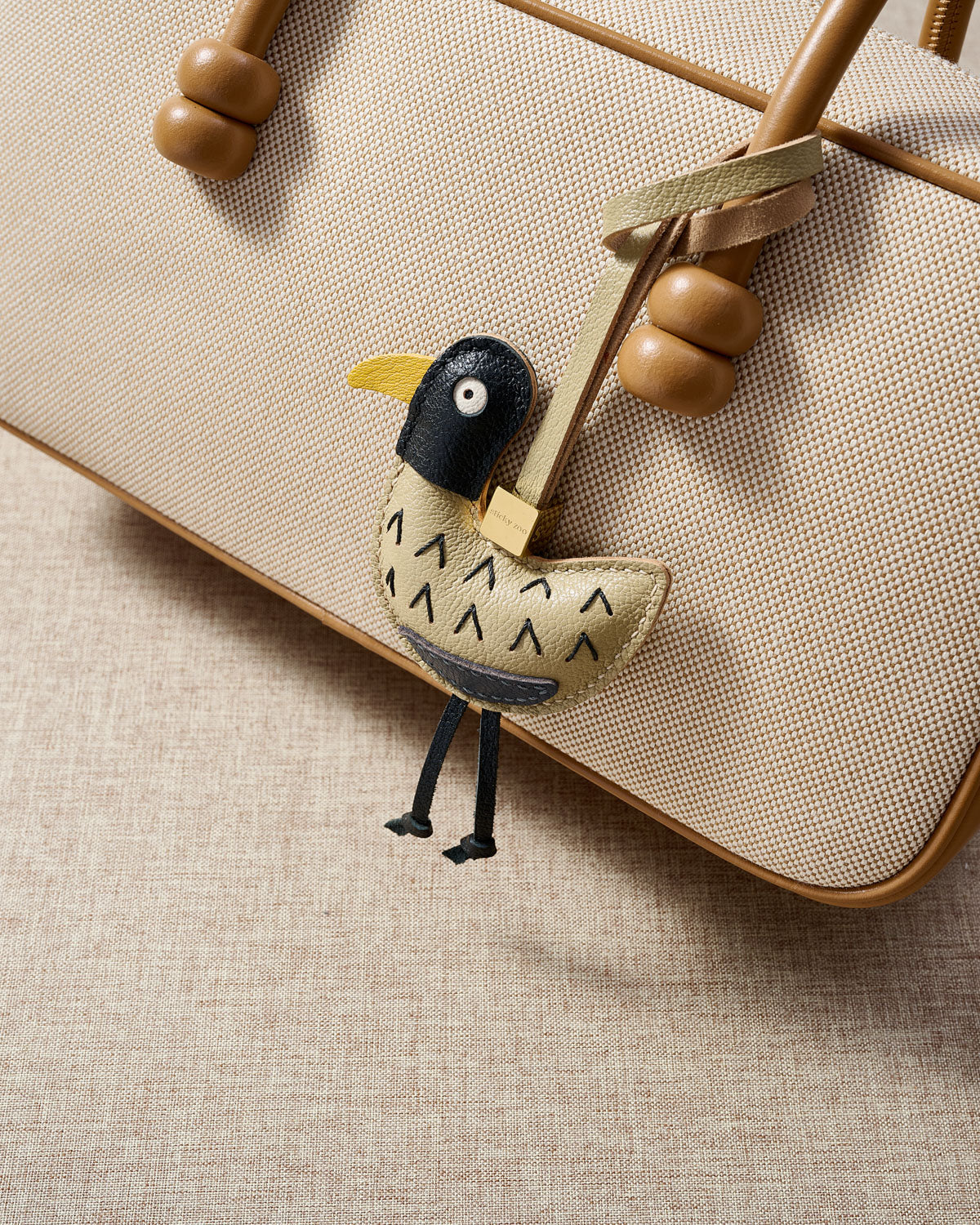 Gull charm styled on a bag, front — a small, specific piece that turns a simple bag into a personal one.