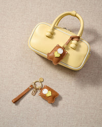 Close-up of the teddy bear charm — hand-cut and hand-stitched panels of French Alran goatskin. Every layer by hand.