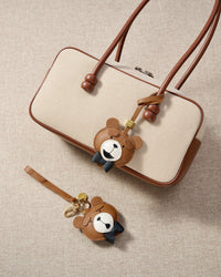 Close-up of the teddy bear charm — hand-cut and hand-stitched panels of French Alran goatskin. Every layer by hand.