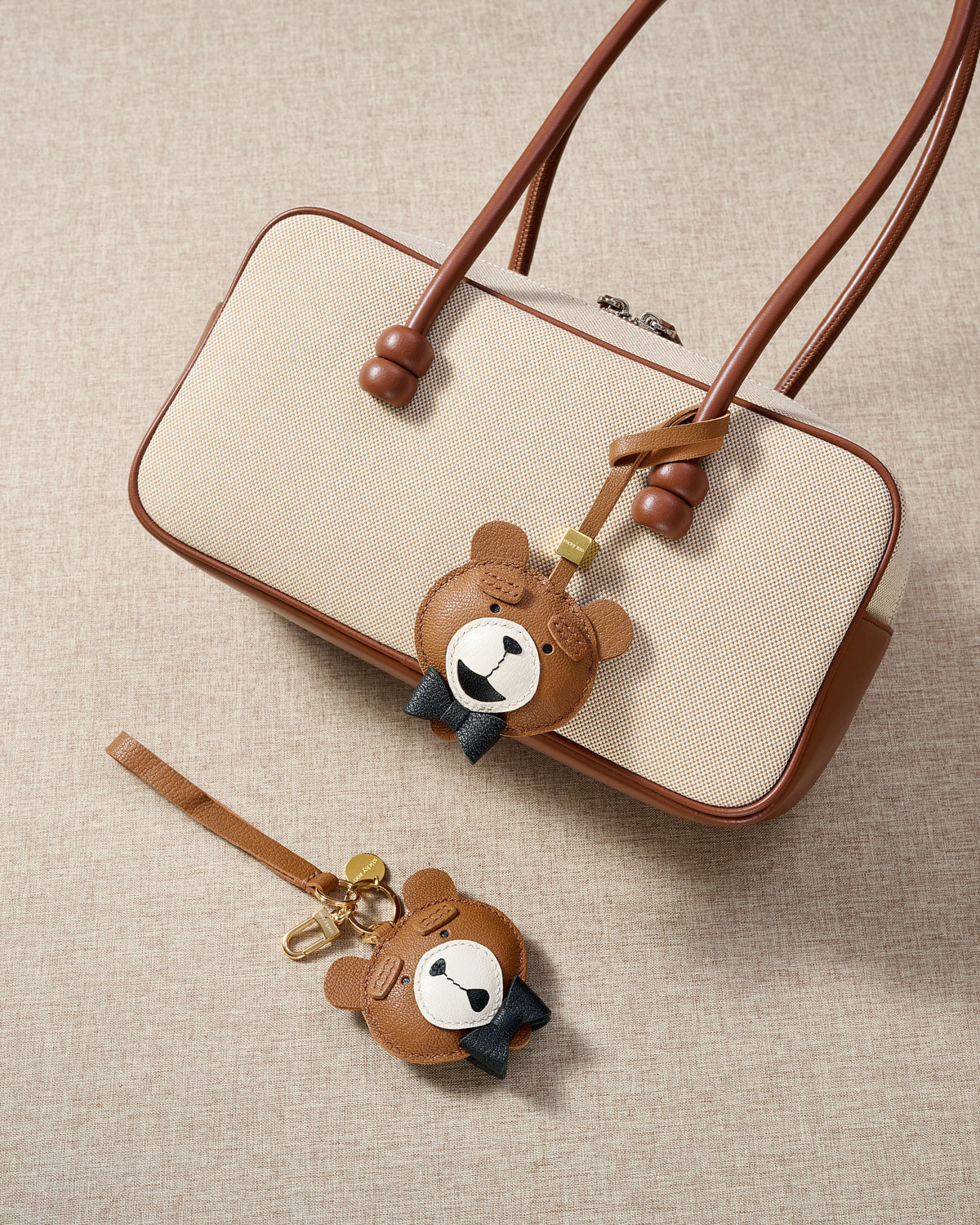 Close-up of the teddy bear charm — hand-cut and hand-stitched panels of French Alran goatskin. Every layer by hand.