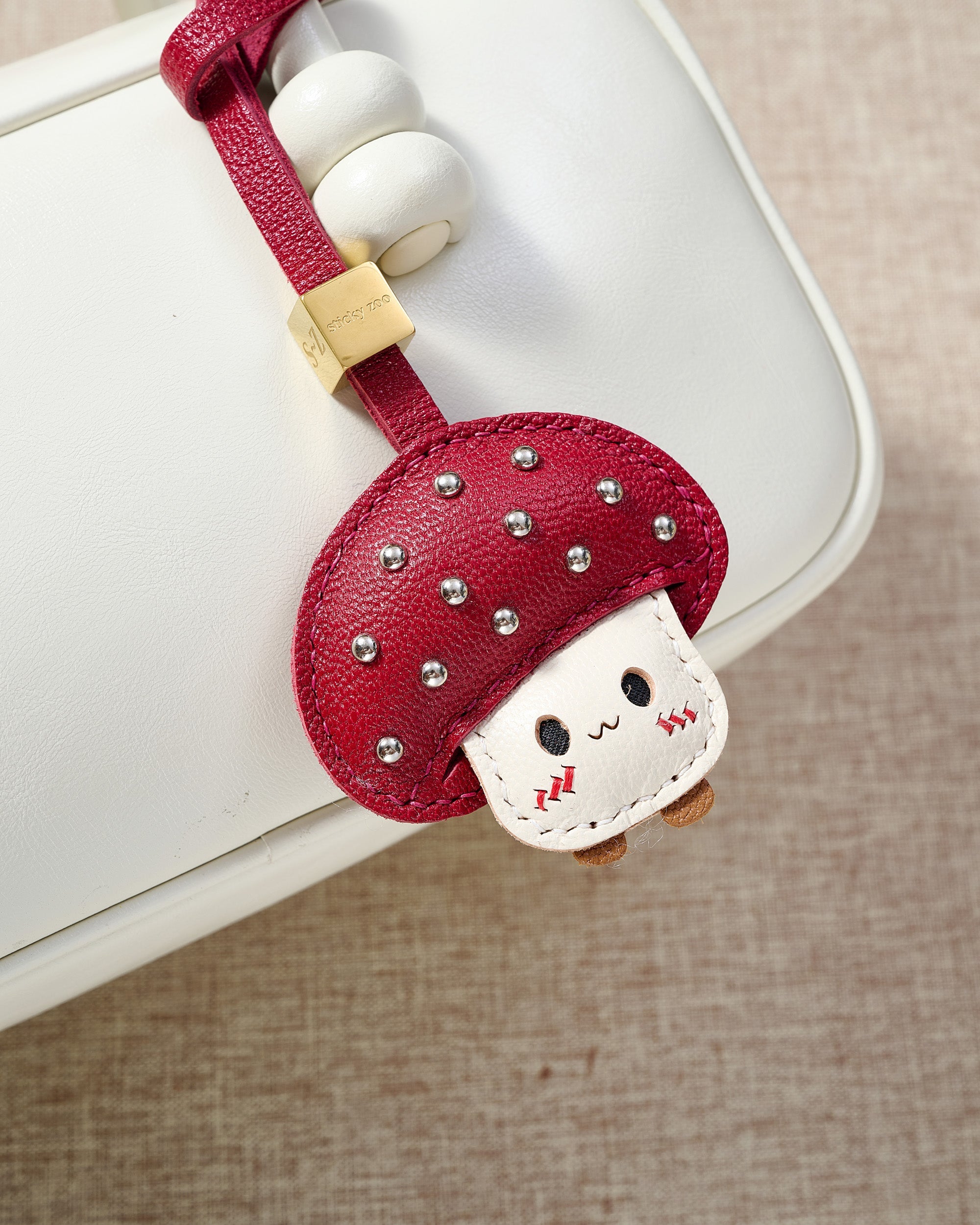 STICKYZOO Mushroom Charm — hand-cut, hand-stitched mushroom cap with cream face in French Alran goatskin. Designed in Amsterdam.