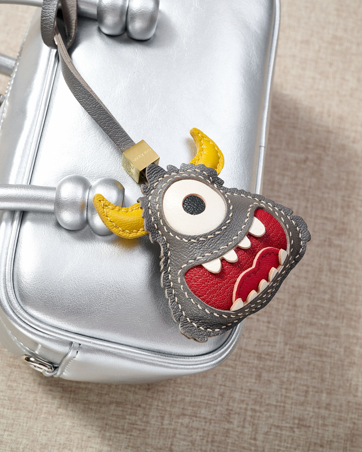 Little monster charm styled on a bag — a small, specific piece that turns a simple bag into a personal one.