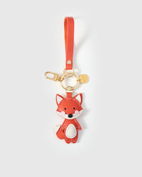 Both editions of the fox charm — leather strap loop for bags, or 18K gold-plated keychain clip.