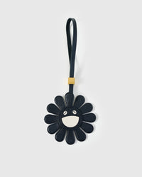 STICKYZOO Night Flower Charm — black French Alran goatskin petals with cream smiley face centre, gold-plated hardware. 3-day handmade piece.