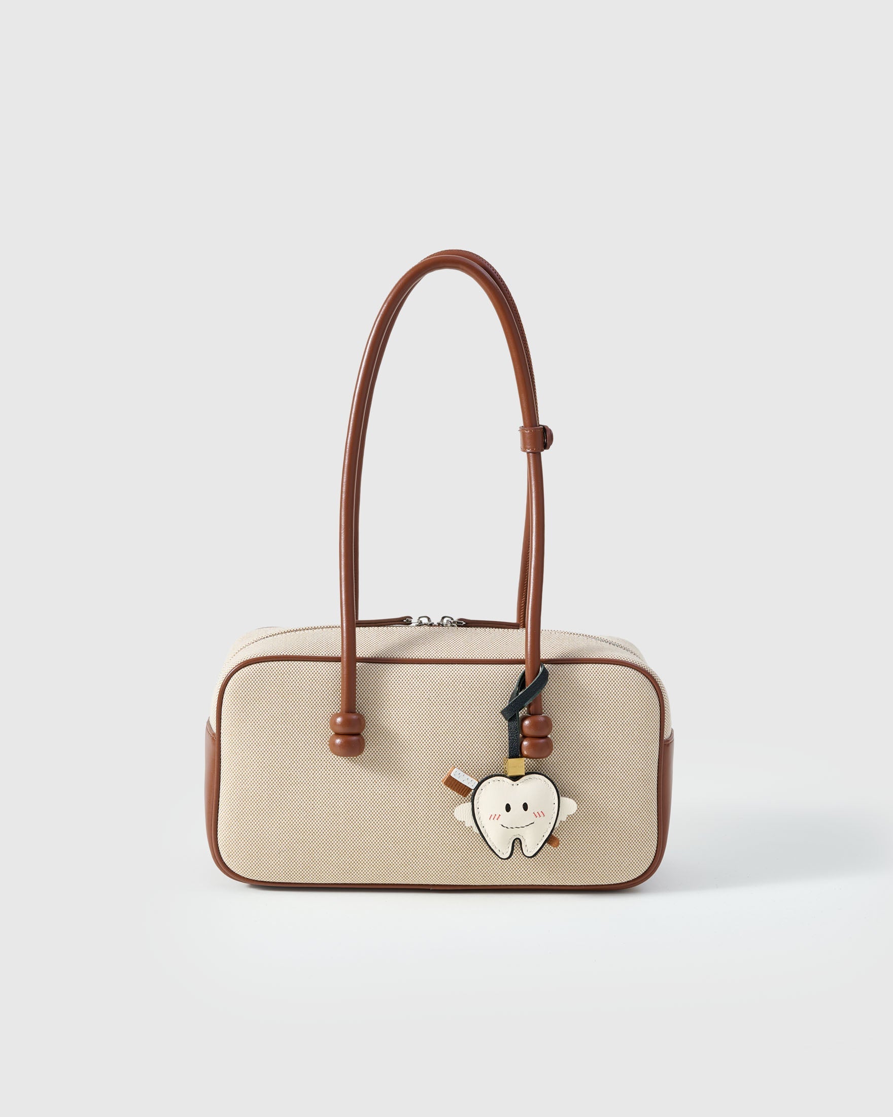 Tooth fairy charm styled on a bag — a small, specific piece that turns a simple bag into a personal one.