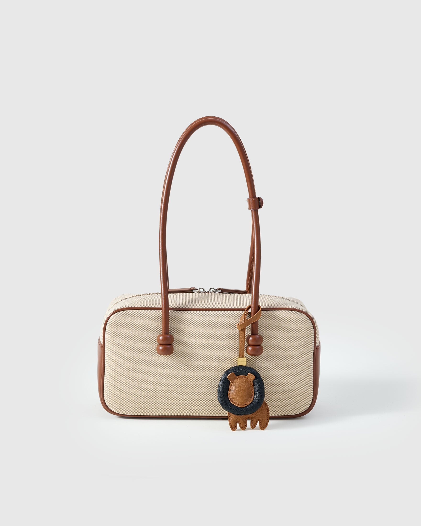 LION CHARM charm styled on a bag — a small, specific piece that turns a simple bag into a personal one.