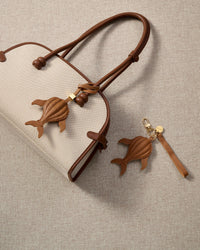 Close-up of the caramel whale — cream hand-stitched seams running along the 3D body, side fins and split tail. Every panel by hand.