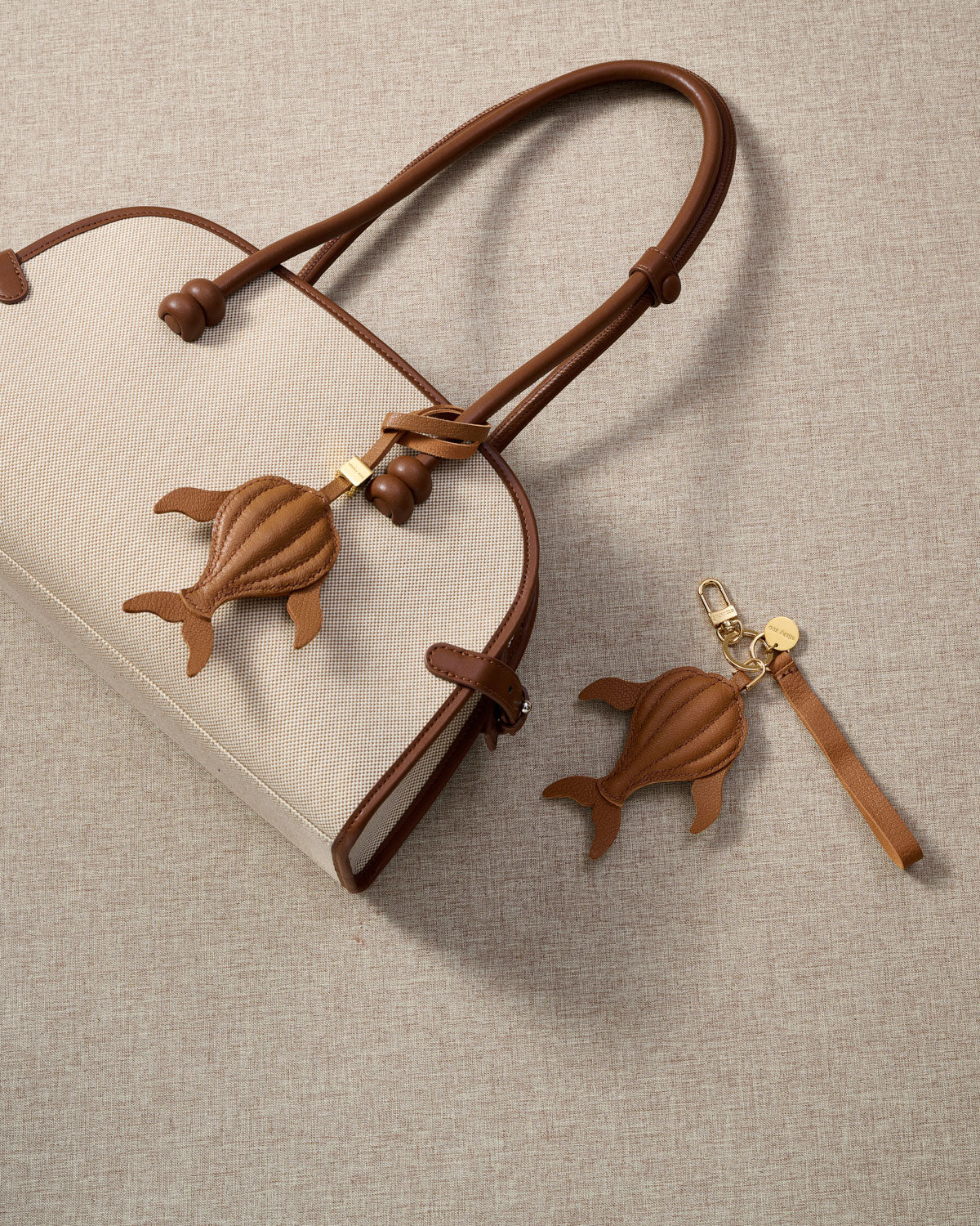 Close-up of the caramel whale — cream hand-stitched seams running along the 3D body, side fins and split tail. Every panel by hand.