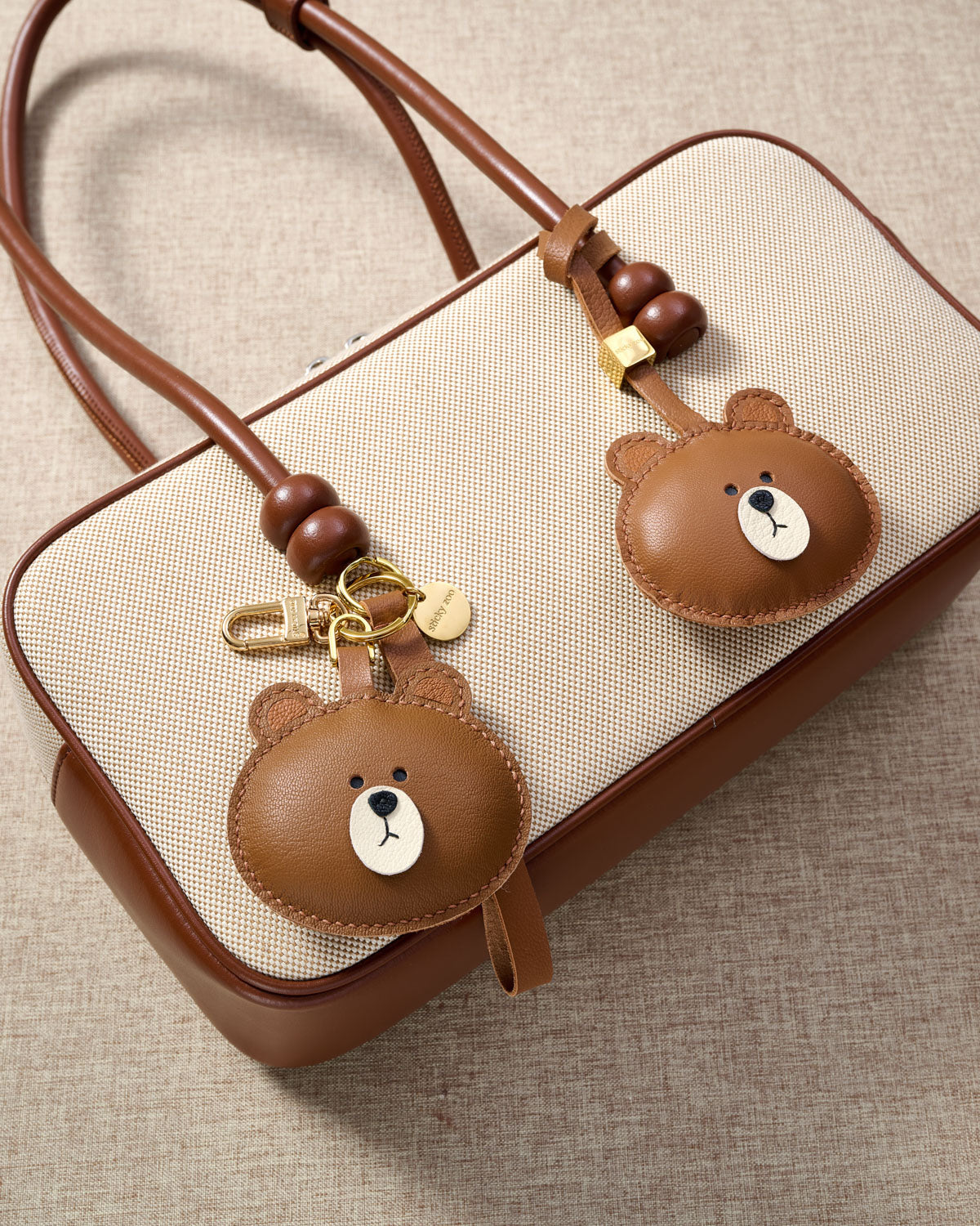 CUDDLY BEAR CHARM charm styled on a bag — a small, specific piece that turns a simple bag into a personal one.