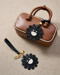STICKYZOO Night Flower Charm — hand-cut, hand-stitched black petals with smiley face centre in French Alran goatskin. Designed in Amsterdam.
