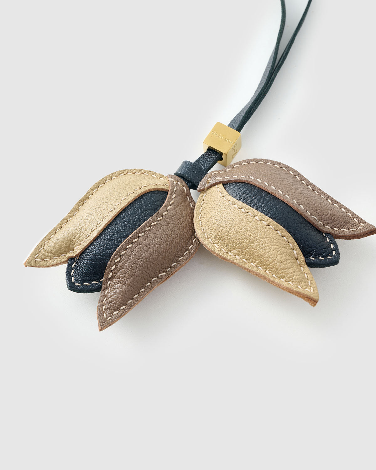 STICKYZOO Tulip Charm clipped to a handbag — handmade French Alran goatskin in gold, taupe, and dark. 3-day artisan build.