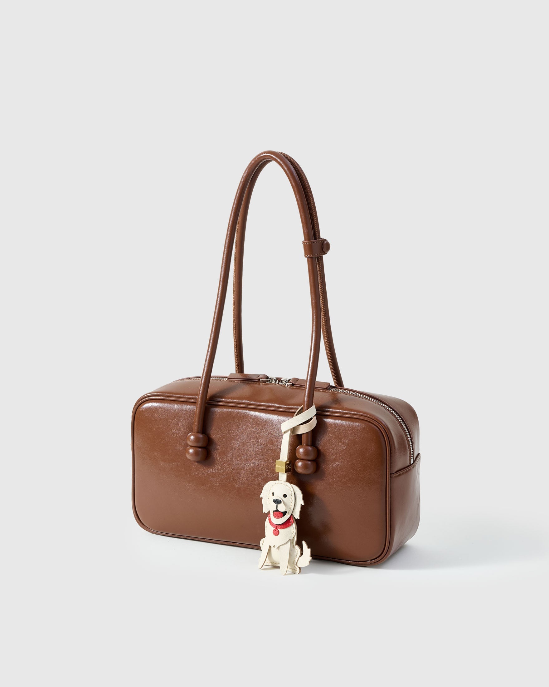 Golden Retriever leather bag charm shown in both attachment options — handmade French Alran goatskin, dual attachment. STICKYZOO Amsterdam design.
