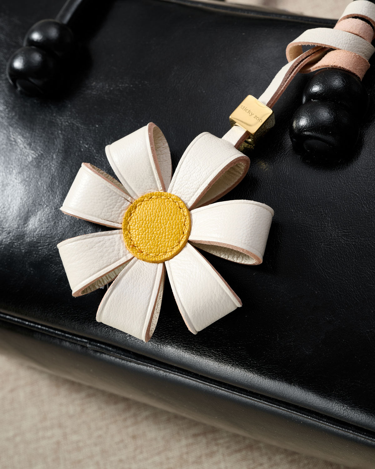 STICKYZOO Daisy Bag Charm — hand-cut, hand-stitched 3D folded daisy petals in French Alran goatskin. Designed in Amsterdam.