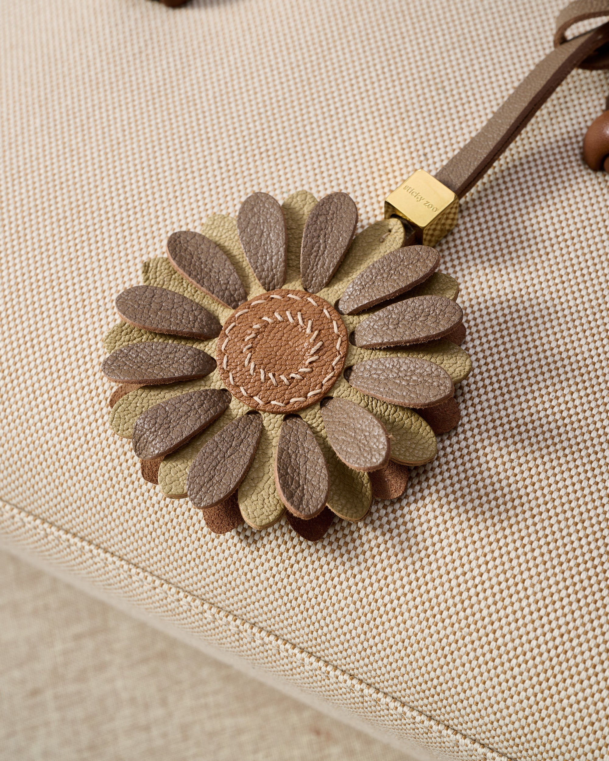 STICKYZOO Daisy Charm — hand-cut, hand-stitched layered daisy petals with tan centre in French Alran goatskin. Designed in Amsterdam.