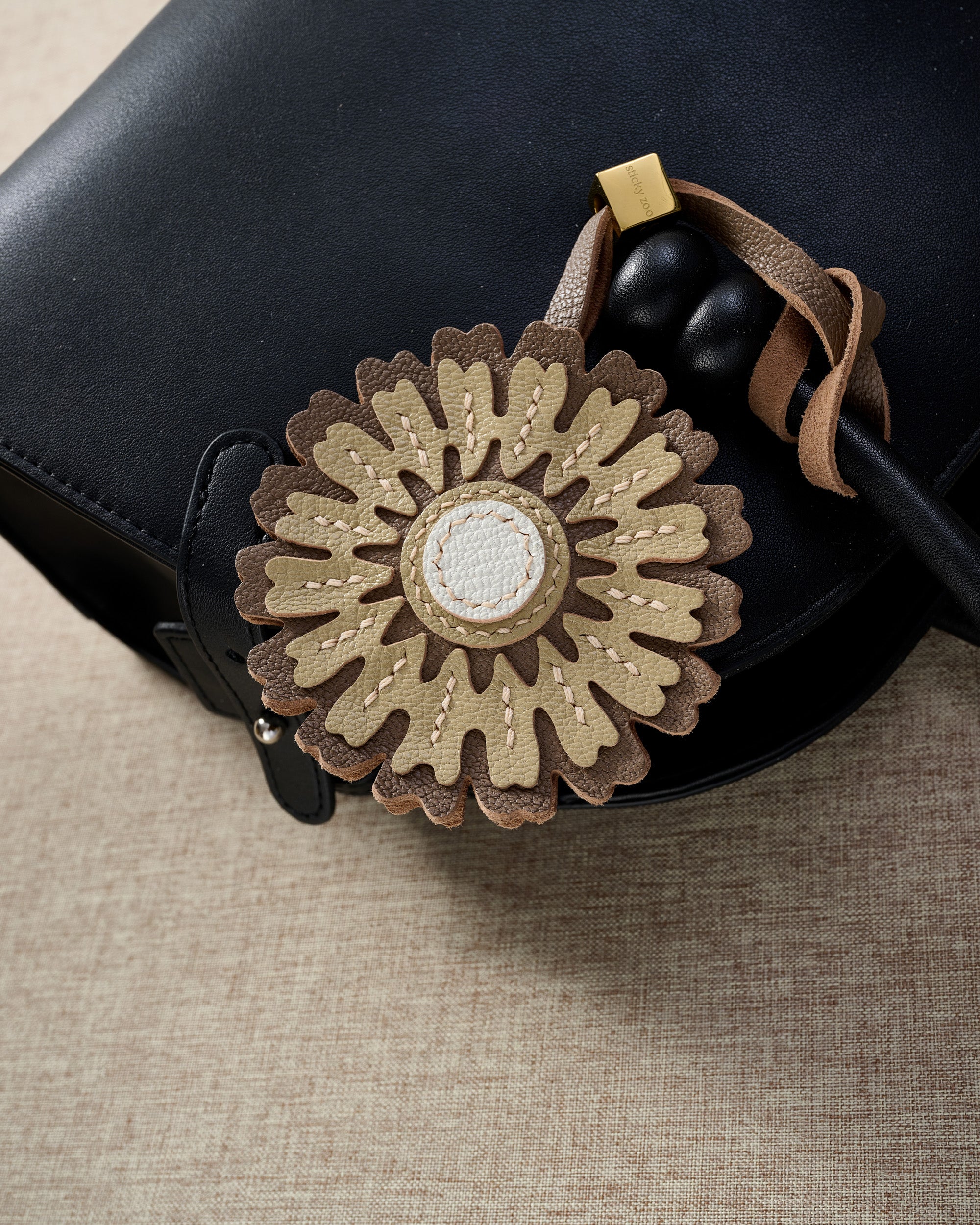 Close-up of STICKYZOO Sunflower Charm — full-grain French Alran goatskin from Tarn, France. Layered sunflower petals with white centre. 3-day handmade piece.