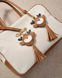 Close-up of the deer charm — hand-cut and hand-stitched panels of French Alran goatskin. Every layer by hand.