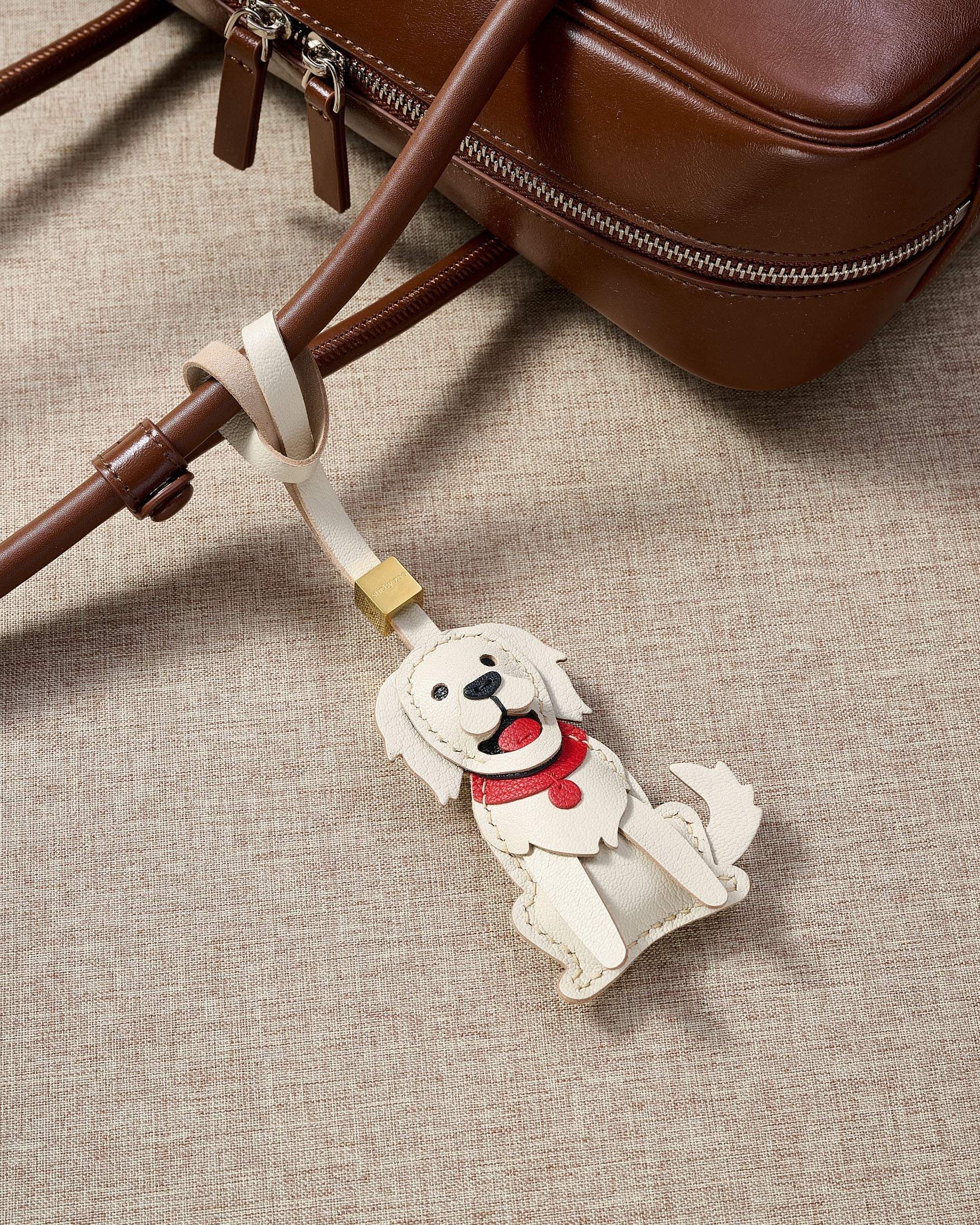 Close-up of handmade Golden Retriever leather bag charm — hand-layered paws, ears, and body panels in French Alran goatskin. STICKYZOO 5-day build.
