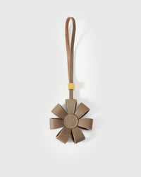 STICKYZOO Daisy Bag Charm in warm taupe French Alran goatskin — folded dimensional petals with tonal centre disc, 18K gold-plated hardware. 3-day handmade piece.