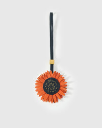 STICKYZOO Sunflower Charm — rust-orange French Alran goatskin petals with dark stitched centre disc, 18K gold-plated hardware. 3-day handmade piece.