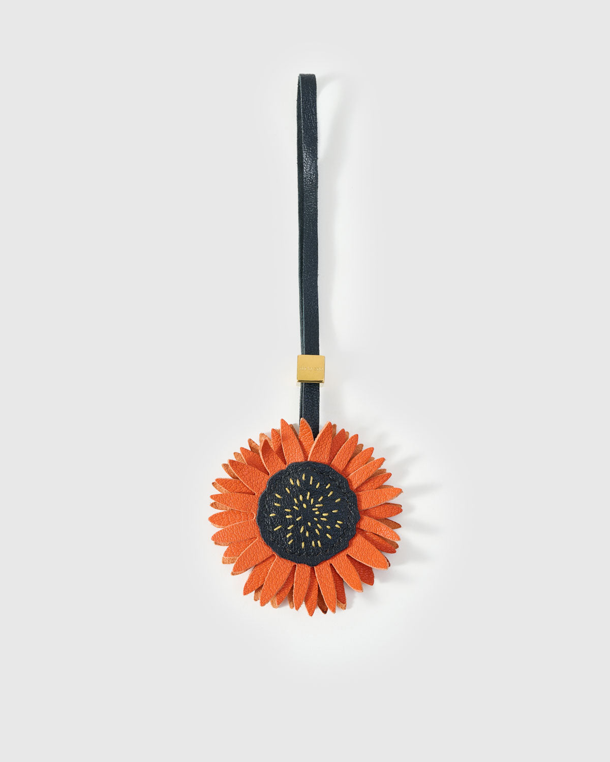 STICKYZOO Sunflower Charm — rust-orange French Alran goatskin petals with dark stitched centre disc, 18K gold-plated hardware. 3-day handmade piece.