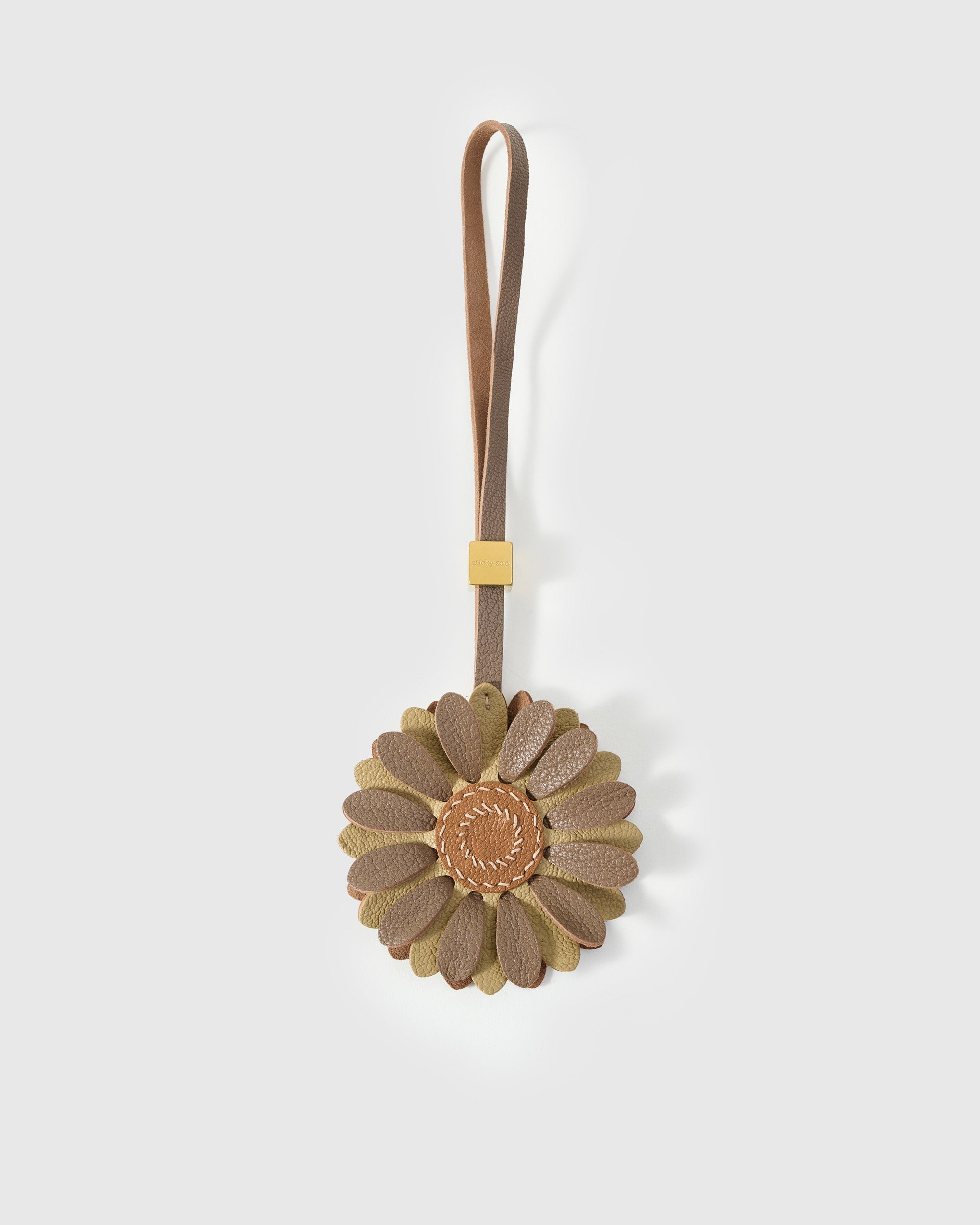 STICKYZOO Daisy Charm — taupe and olive French Alran goatskin petals layered around a warm tan centre disc with hand-stitched seed marks. 3-day handmade piece.
