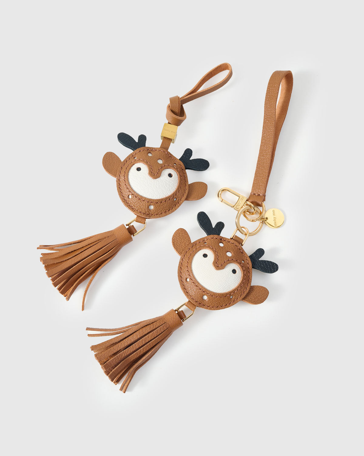 Both editions of the deer charm — leather strap loop for bags, or 18K gold-plated keychain clip.