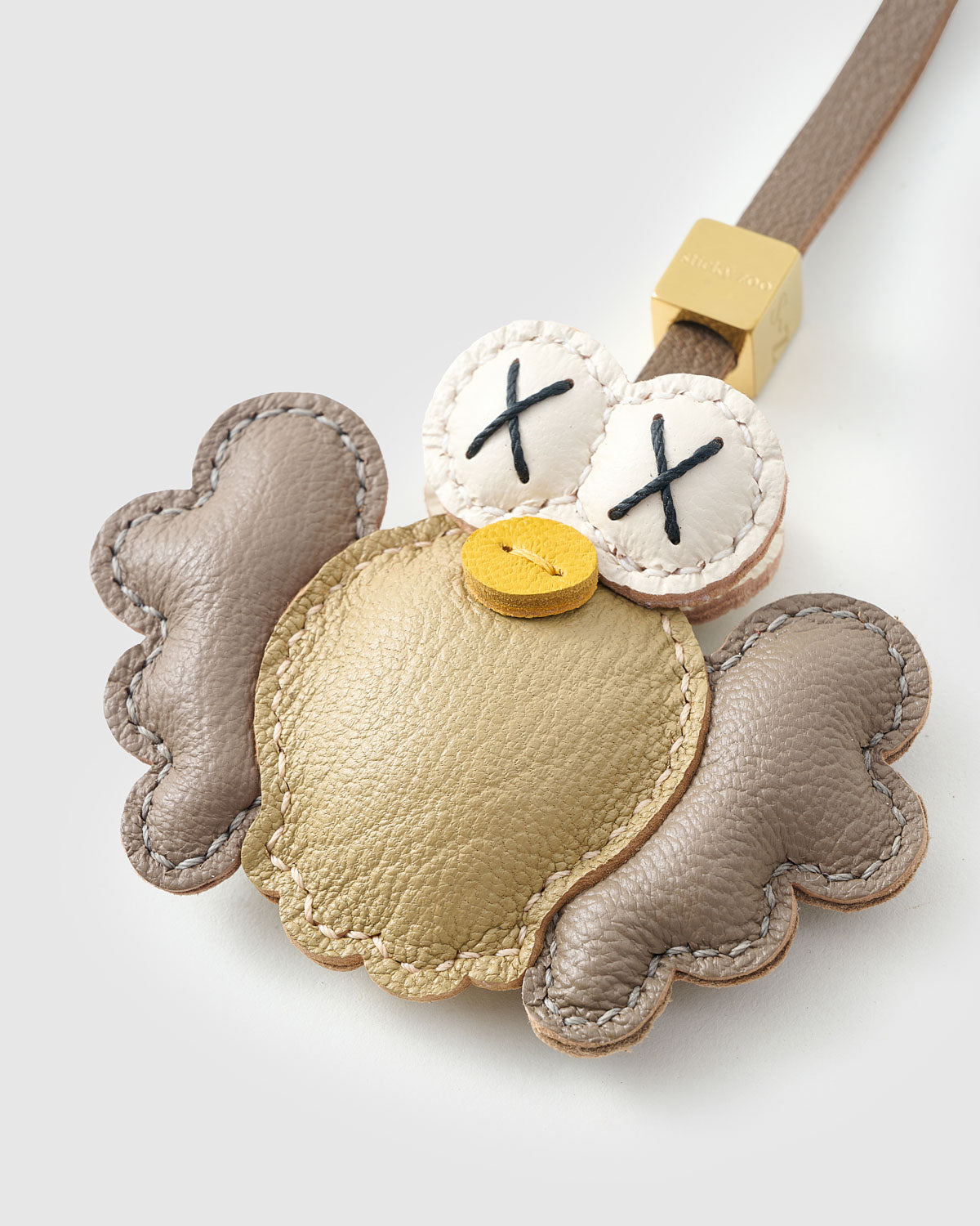 Both editions of gold Hootie — leather strap loop for bags, or 18K gold-plated keychain clip.