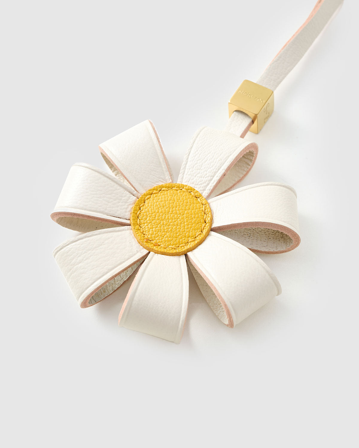 STICKYZOO Daisy Bag Charm clipped to a handbag — handmade French Alran goatskin in white with yellow centre. 3-day artisan build.