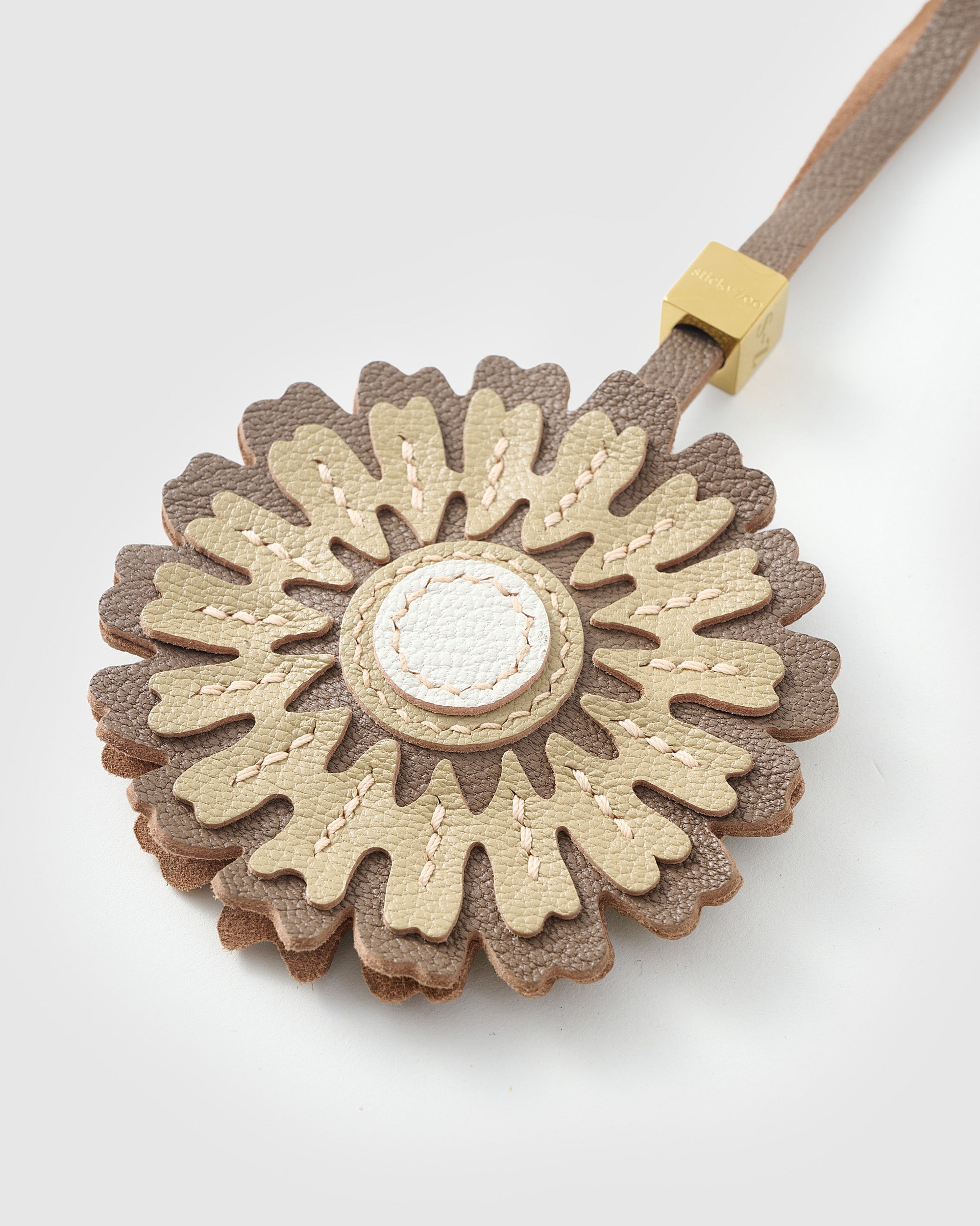 STICKYZOO Sunflower Charm clipped to a handbag — handmade French Alran goatskin in cream and olive over brown. 3-day artisan build.