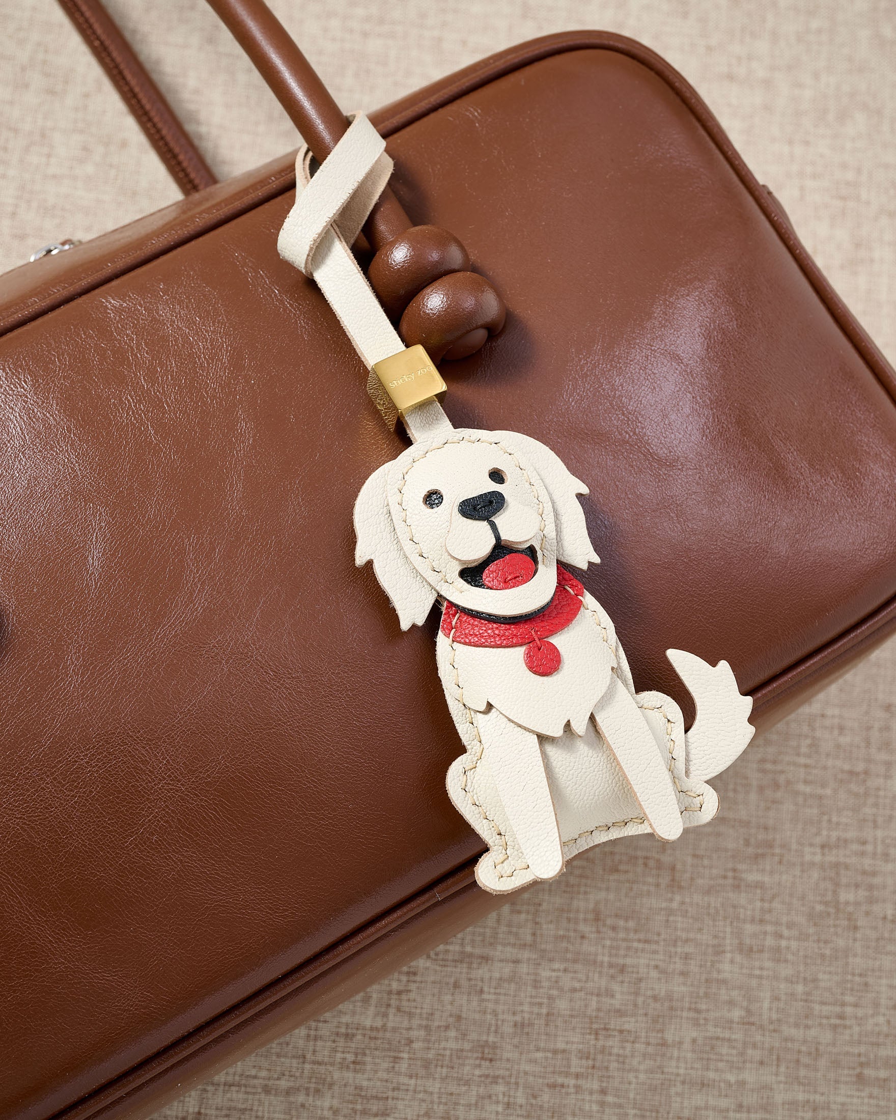 Handmade Golden Retriever leather bag charm on a handbag — 5 days of hand-cutting, stitching, and layering in French Alran goatskin. STICKYZOO.
