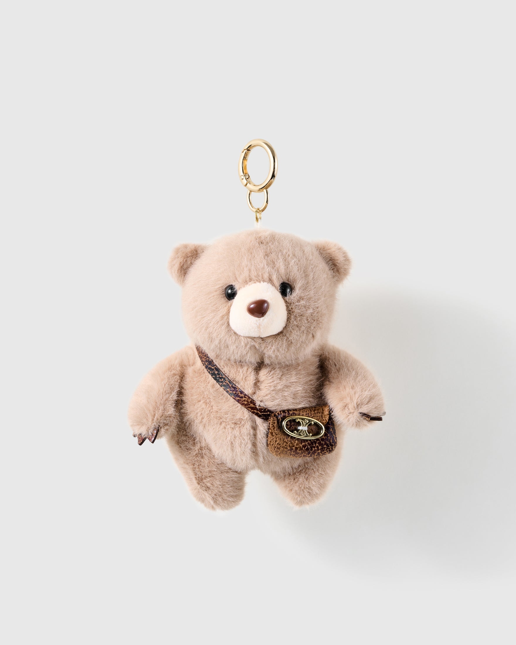 Crossbody Teddy Plush Charm with soft taupe plush, stitched paws and a tiny brown bag give the bear an everyday dressed-up detail on a light background