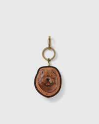 STICKYZOO Clementine Chow Chow portrait charm with a broad caramel face, dark muzzle, red tongue, stitched dark border, and gold-tone ring-and-clip hardware on a pale background