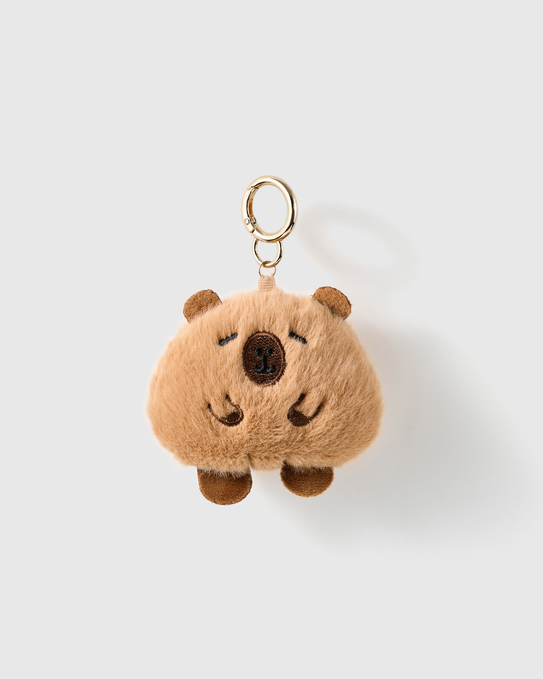 Sleepy Capybara Plush Charm with the rounded brown body, tiny ears and closed embroidered eyes keep the character simple and calm on a light background