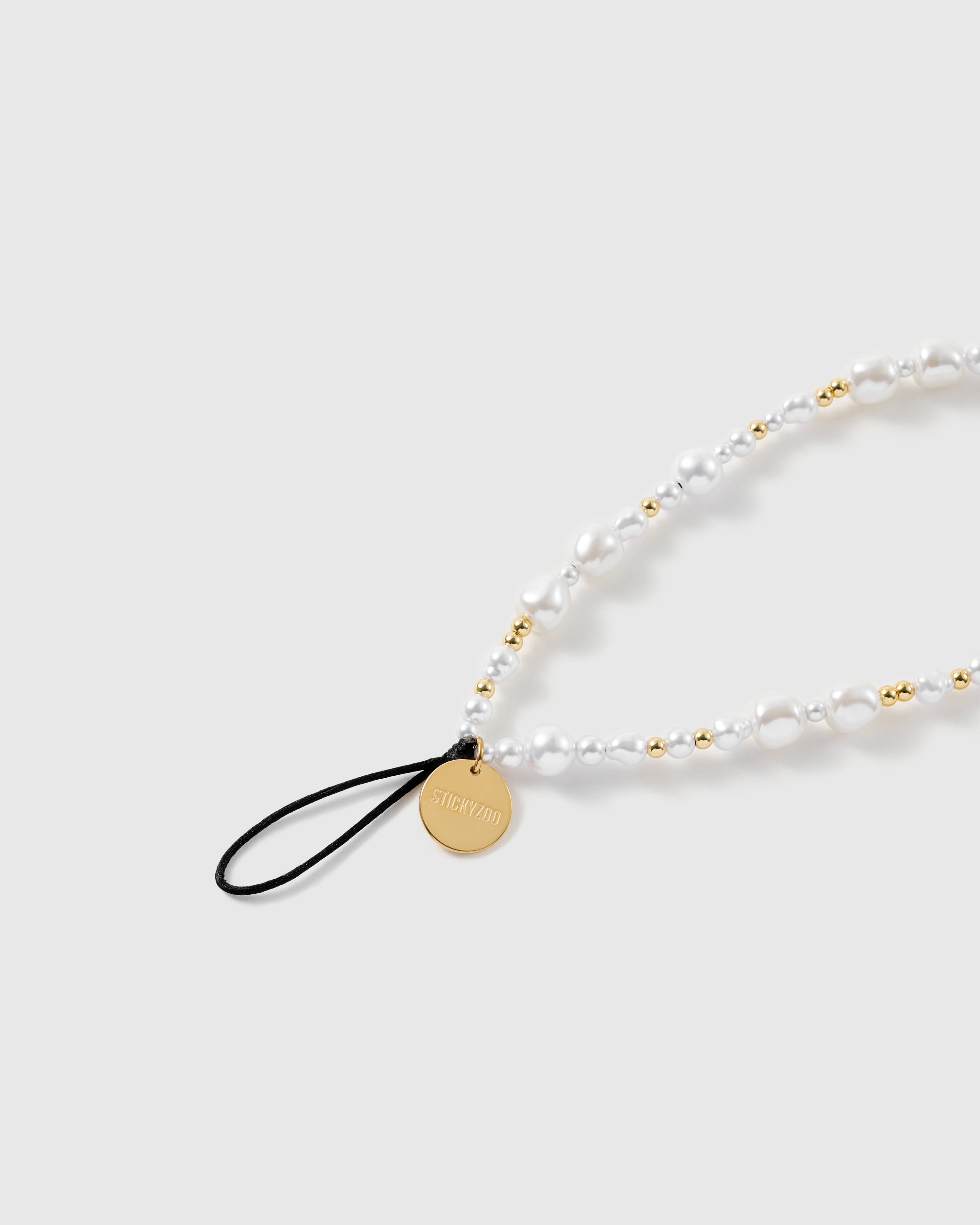 Close view of the mixed faux-pearls, gold-tone ball beads, engraved STICKYZOO disc and black attachment loop.