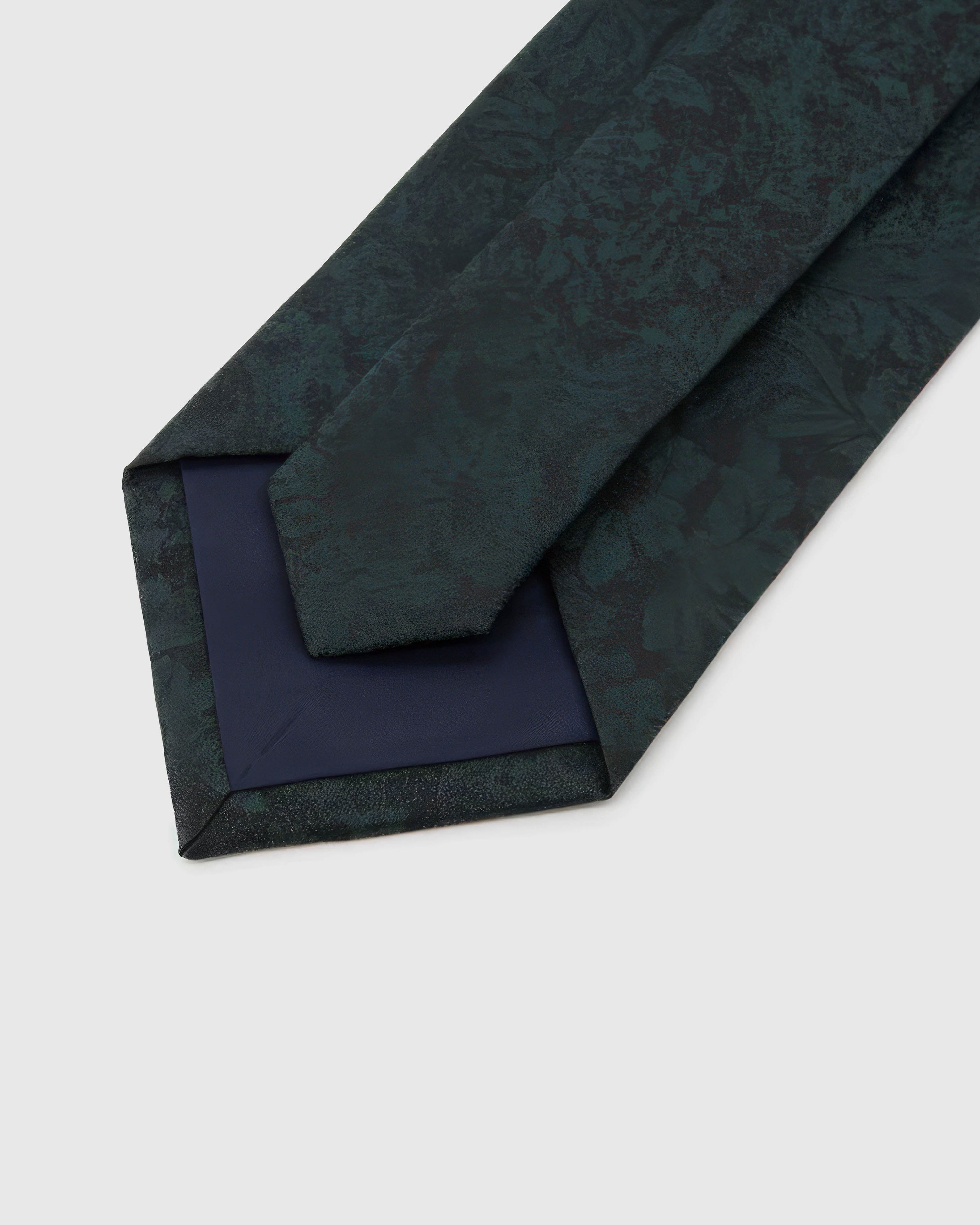 Forest Shadow Floral Tie detail showing tonal shadow florals and foliage, raised thread and the tactile deep forest teal silk surface.
