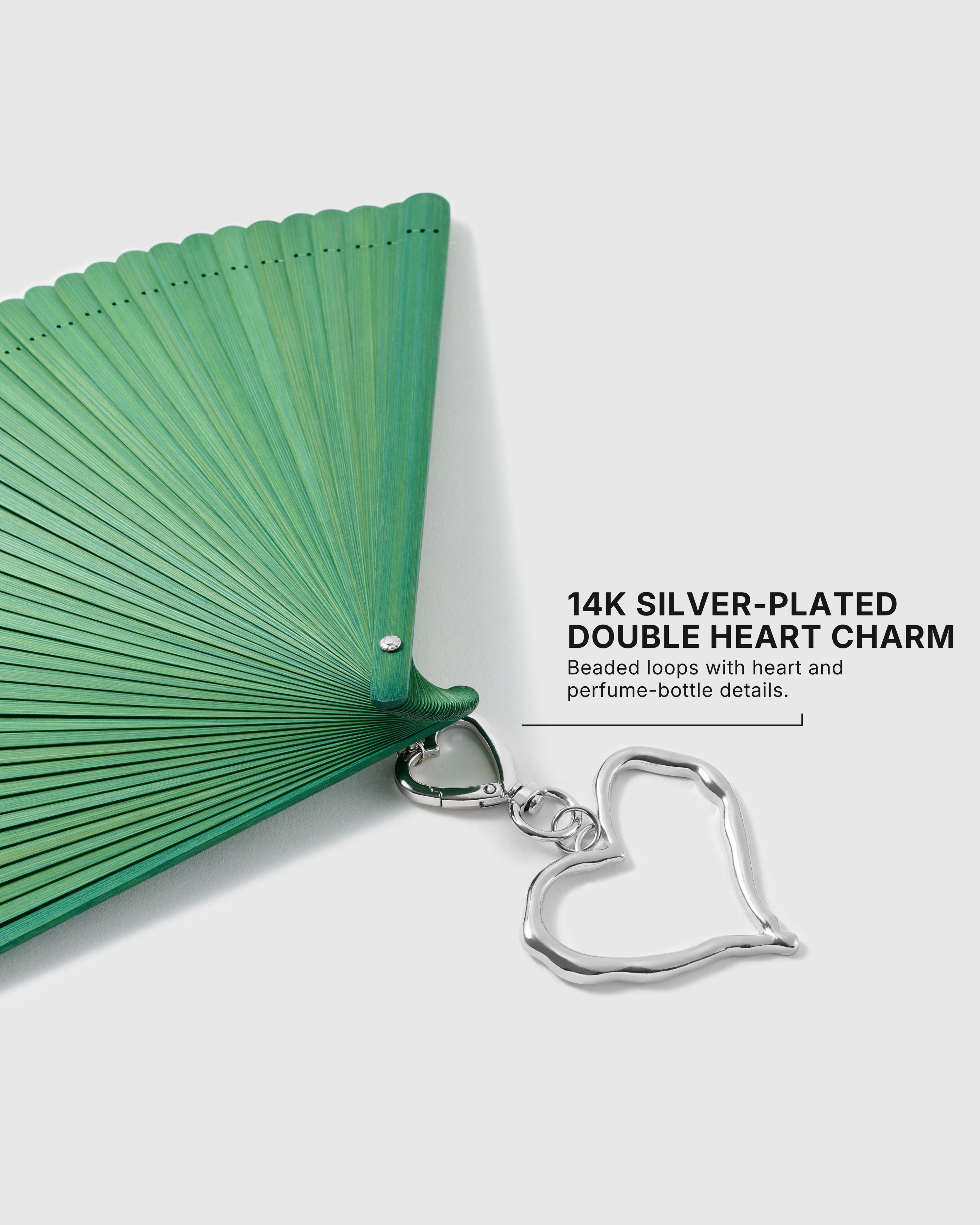 Close-up of 14K silver-plated open-heart charm attached to the green hand fan