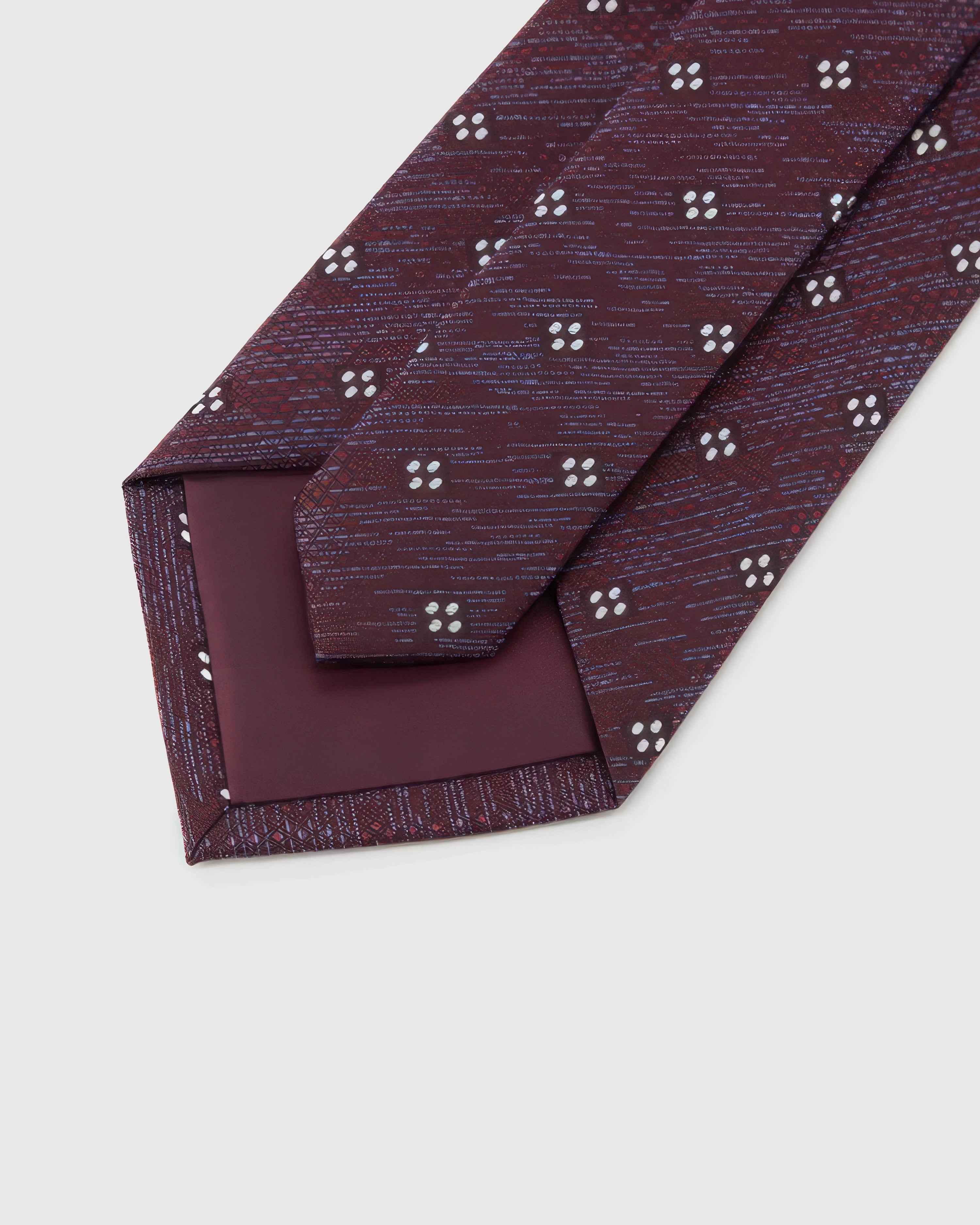 Claret Four-Dot Tie detail showing claret crosshatch with white four-dot clusters and the tactile silk surface.