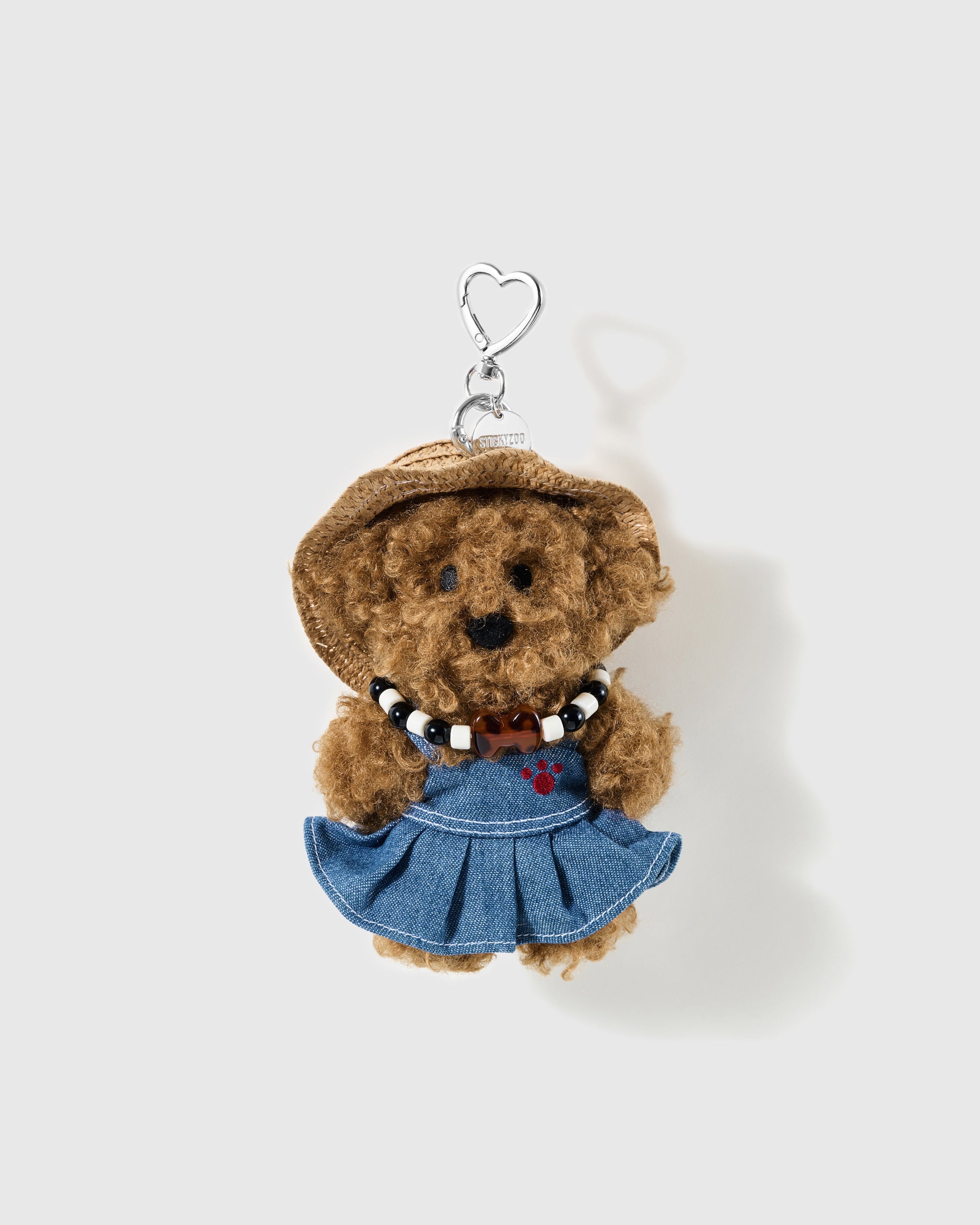 Brown curly poodle charm in a woven hat and denim-look dress with a beaded collar and silver-colour heart clip