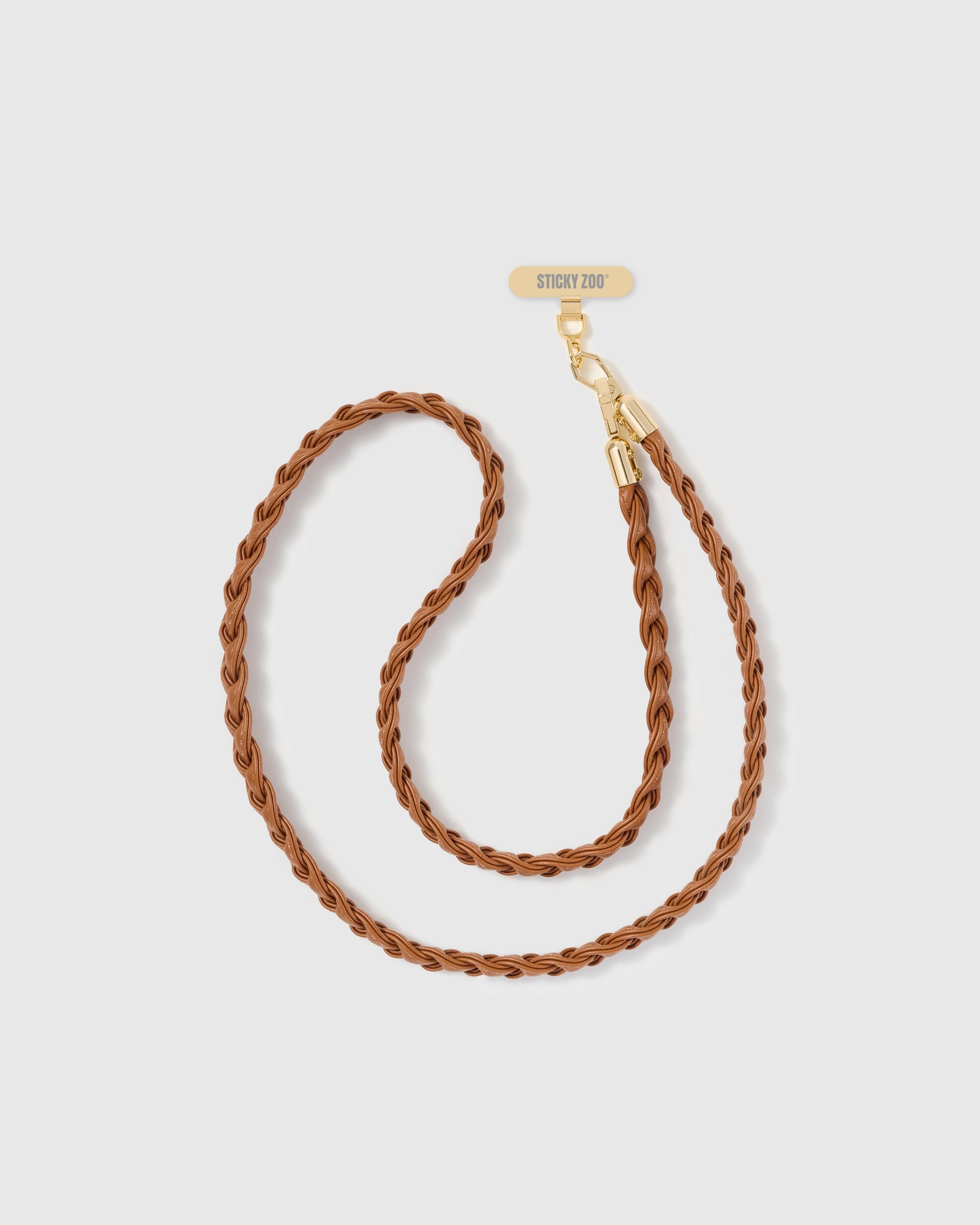 Full-length hand-braided cognac phone strap shown with gold-plated hardware and included Phone Strap Card